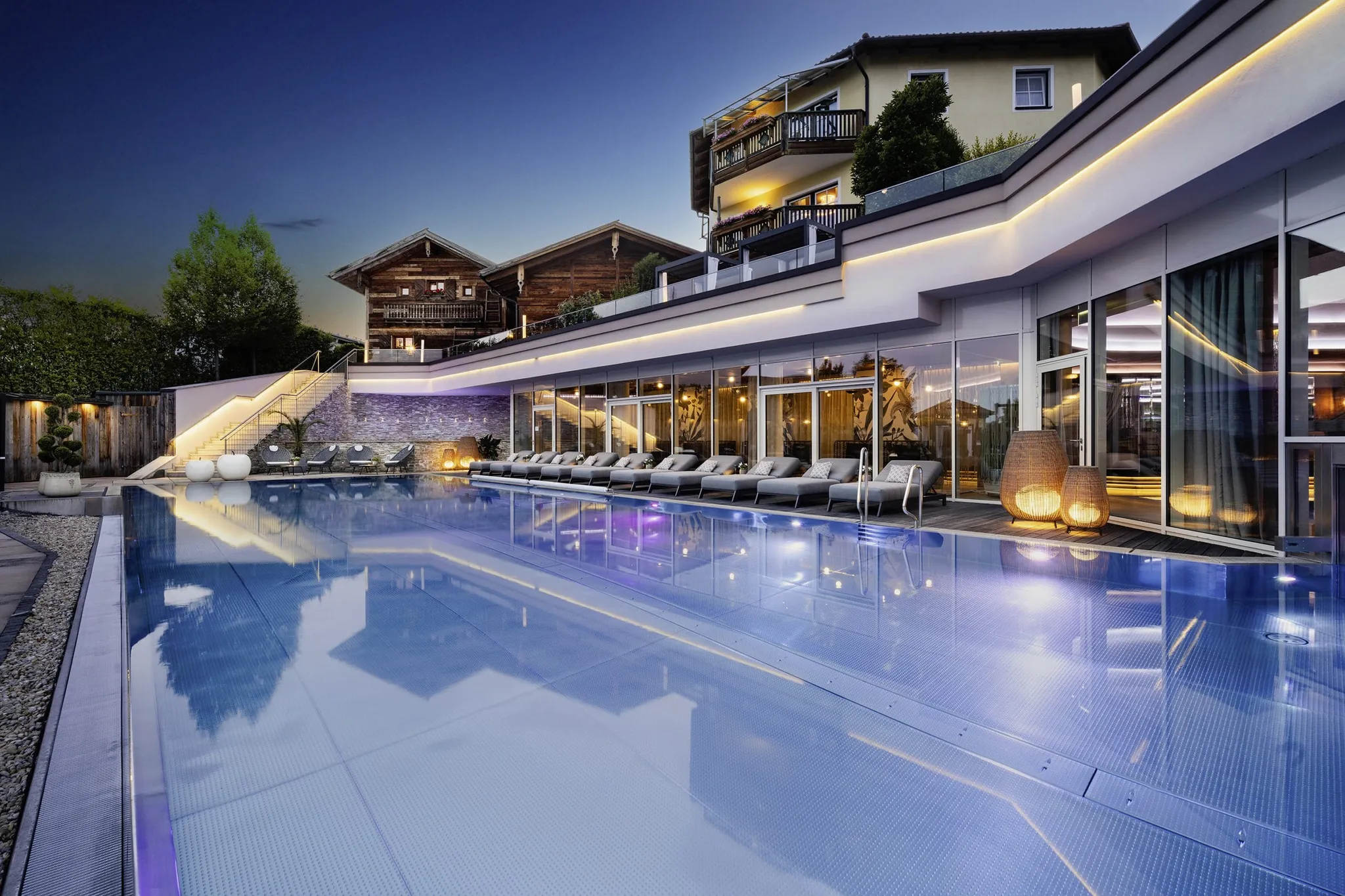 Outdoorpool vor der Fassade mit Lichtleiste im Abendlicht im Wellnesshotel Jagdhof Röhrnbach
