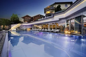 Outdoorpool vor der Fassade mit Lichtleiste im Abendlicht im Wellnesshotel Jagdhof Röhrnbach