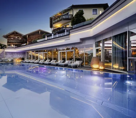 Outdoorpool vor der Fassade mit Lichtleiste im Abendlicht im Wellnesshotel Jagdhof Röhrnbach