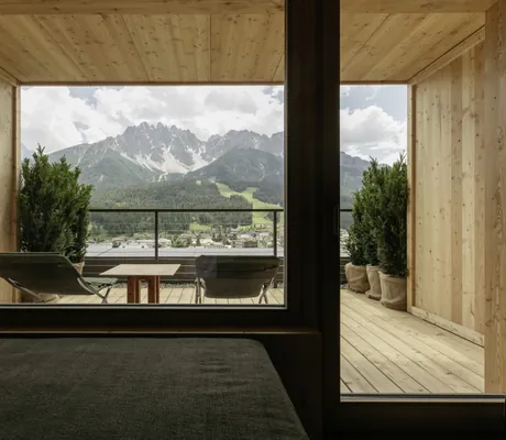 Holzterrase mit zwei Liegestühlen und Tuyenbüschen mit Blick auf die Dolomiten im Naturhotel Leitlhof