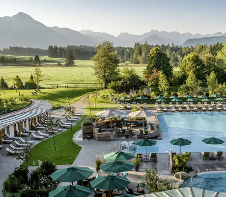 Blick auf die Wasserwelt des Wellness Parks mit aufgespannten grünen Sonnenschirmen im Sonnenalp Resort