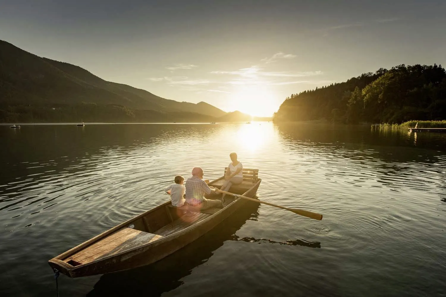 &auml;lteres Paar mit Enkel rudert in der Abendsonne auf dem Fuschlsee im Ebners Waldhof am See