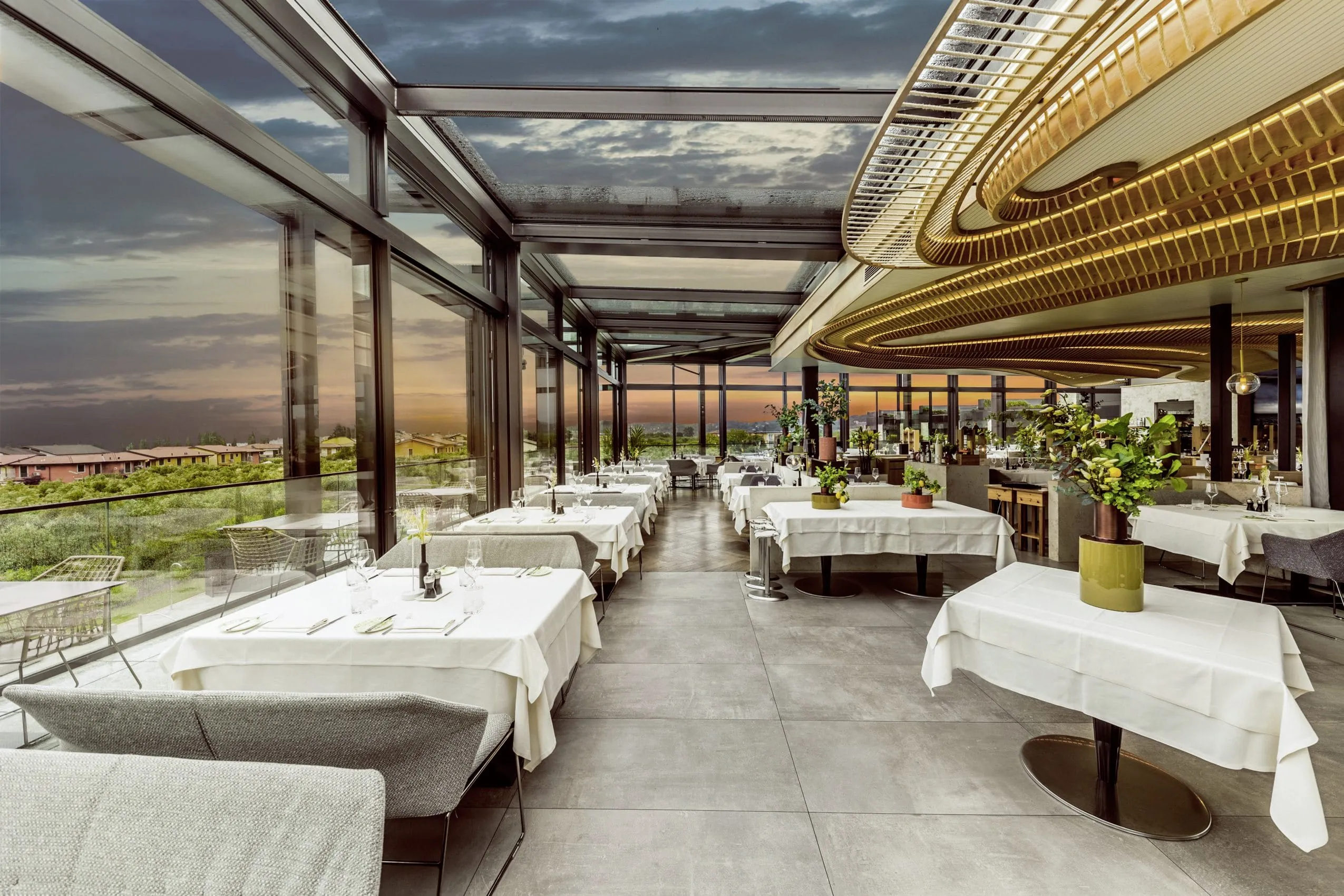 Panoramarestaurant mit Cabriodach aus Stahl und Glas in der Abendd&auml;mmerung im Quellenhof Luxury Resort Lazise