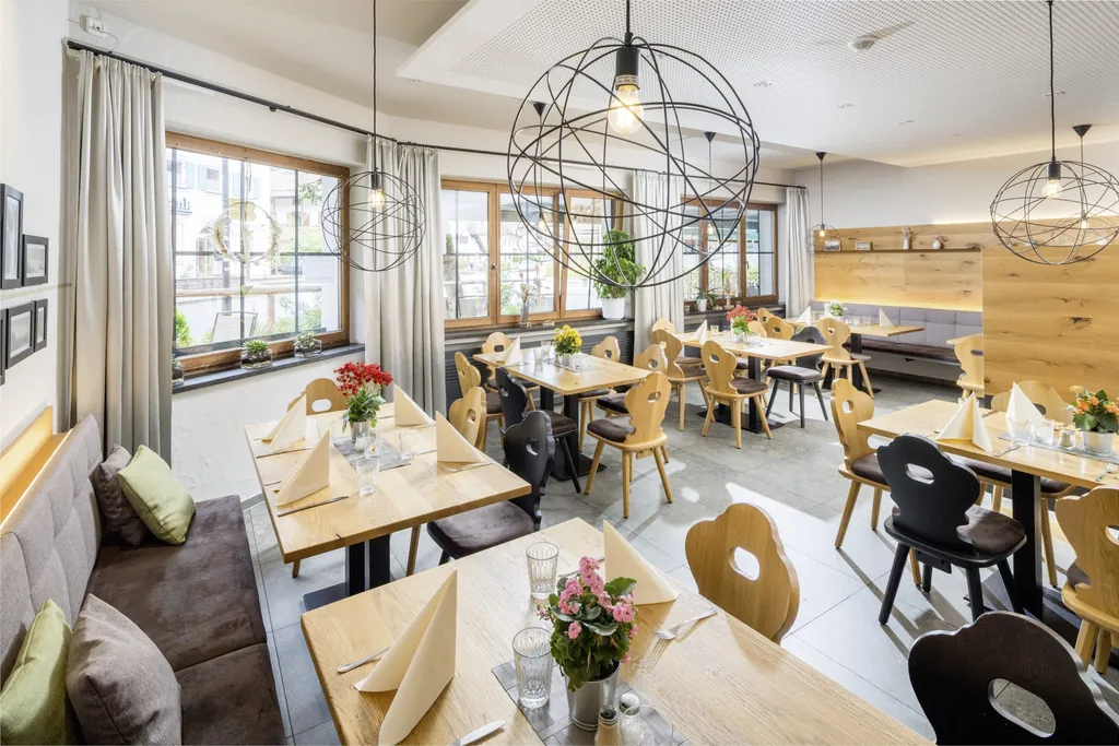 Modern gestalteter Fr&uuml;hst&uuml;cksbereich im Hundesporthotel Wolf in Oberammergau mit eingedeckten Tischen