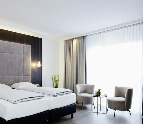 Superior Doppelzimmer in grau-beige mit Bett-Wandhaupt und -polster und zwei Sesseln