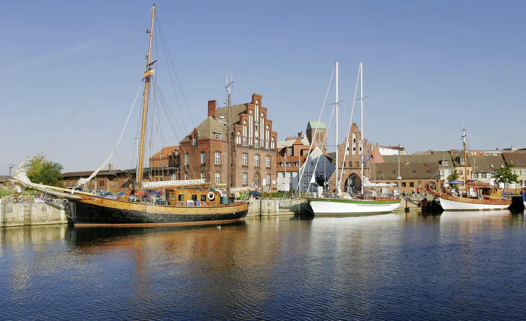 Alter Hafen von Wismar mit Backsteingebäuden im Hintergrund und Schiffen auf der Ostsee