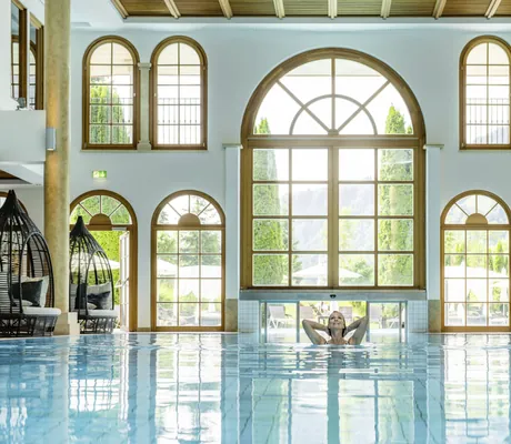Frau im Indoorpool hebt ihre Arme in den Nacken im A-ROSA Kitzbühel