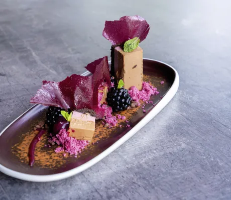 Desserkreation in Weinrot auf braunem Teller im Romantischer Winkel