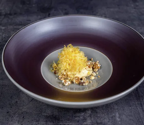 Gericht mit gerösteten Zwiebeln auf dunkellila Teller im Romantischer Winkel