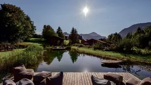 Naturbadesee umgeben von Schilf vor Alpenpanorama des Hotel Oberstdorf