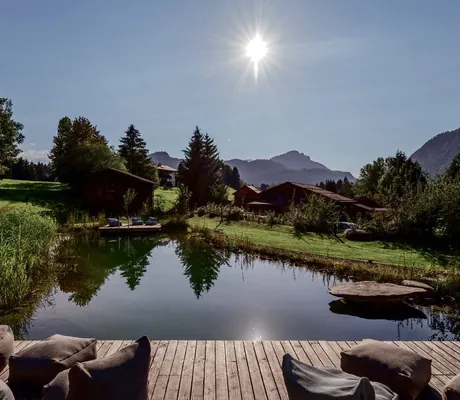 Naturbadesee umgeben von Schilf vor Alpenpanorama des Hotel Oberstdorf