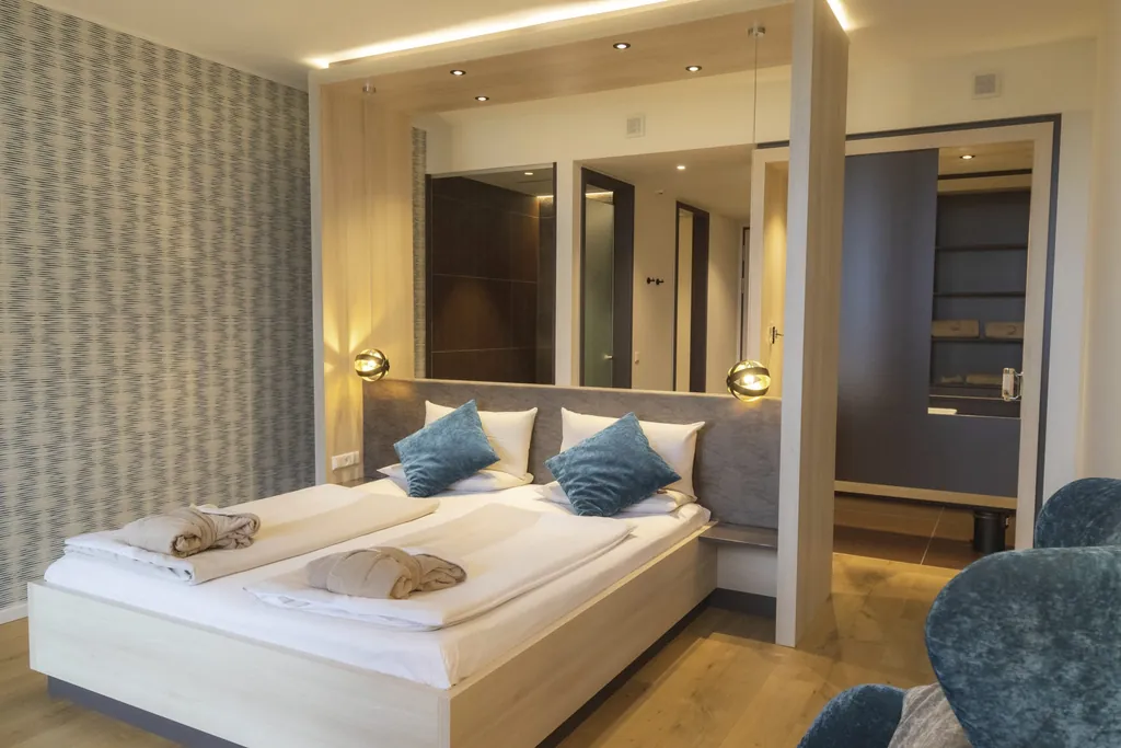 Doppelbett mit türkisen Dekokissen und Trennwand zum Bad in der Bornmühle