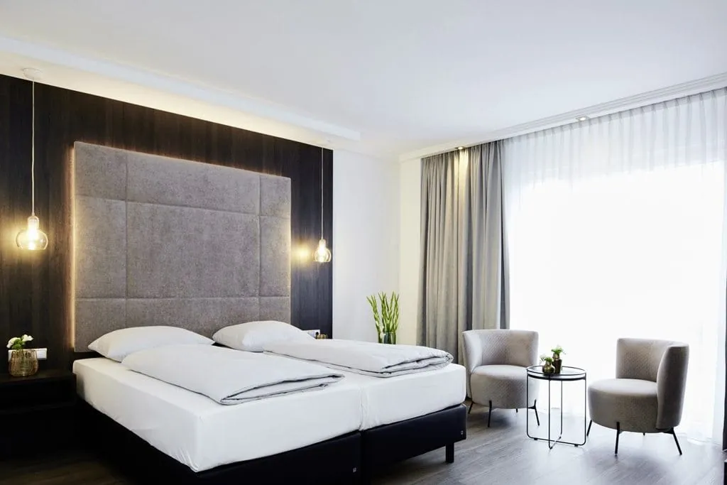 Doppelbett mit grauer Rückwand und Hängeleuchten im Esperanto