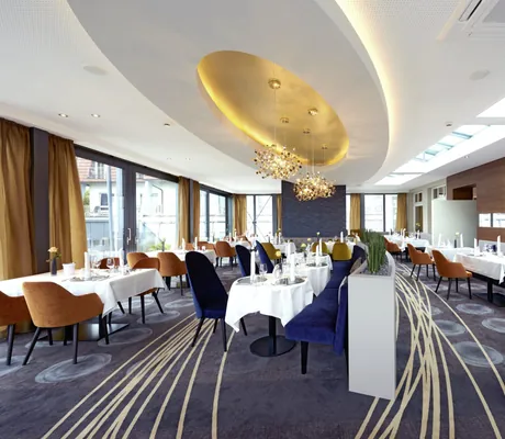 Restaurant mit goldener ovaler Deckenleuchte im Hotel Heinz