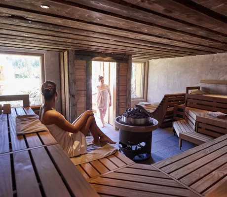 Frau sitzt in der Sauna, während eine zweite zur Türe herein kommt im Hotel Heinz