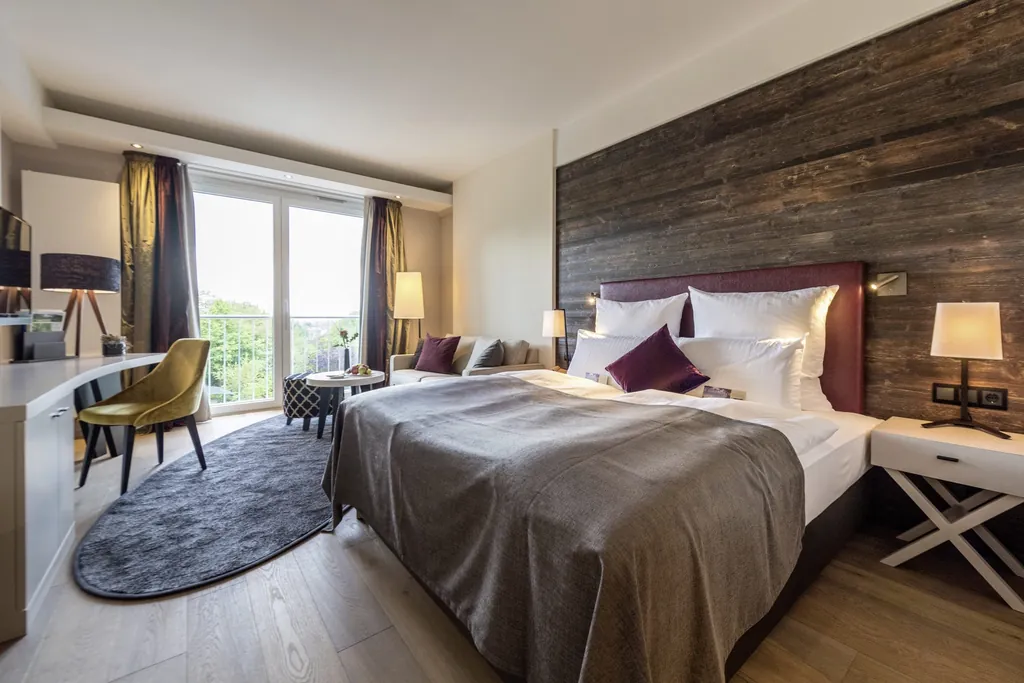 Doppelbett mit althölzernem Bettenrückteil und gelbem Stuhl im Hotel Heinz