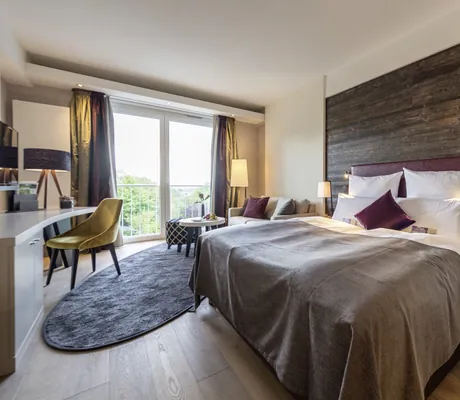 Doppelbett mit althölzernem Bettenrückteil und gelbem Stuhl im Hotel Heinz