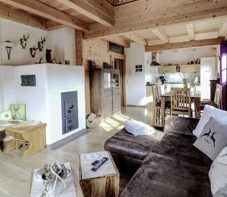 Blick in das Chalet Beim Wartner mit Sofa, Kamin, Galerie und Essbereich