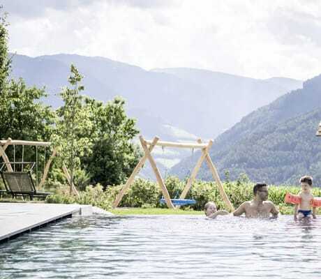 Familie mit zwei Kindern spielt im Außenpool vor dem Spielplatz des Das Mühlwald