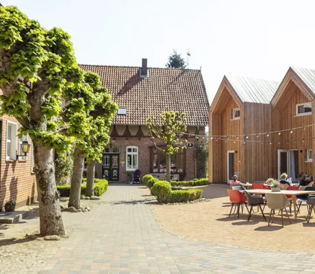 Hof mit bunter Bestuhlung und Blick auf die Holz-Cabins des Landhaus Averbeck