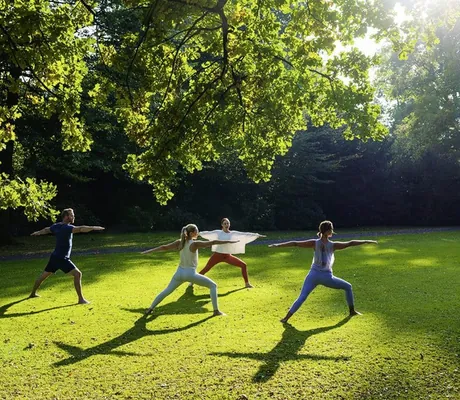 Vier Personen beim Outdoor-Yoga im Garten des Sporthotel Gräflicher Park Health & Balance Resort