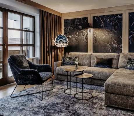 Modern gestaltetes Zimmer im Der Eisvogel Hotel & Spa mit Sofa, Sessel und stylischer Tapete