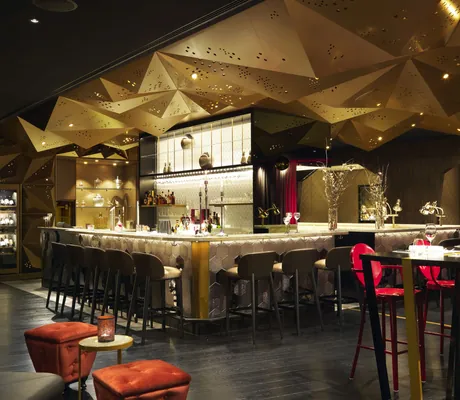 Bar mit illuminierter Rautendecke und roter Bestuhlung