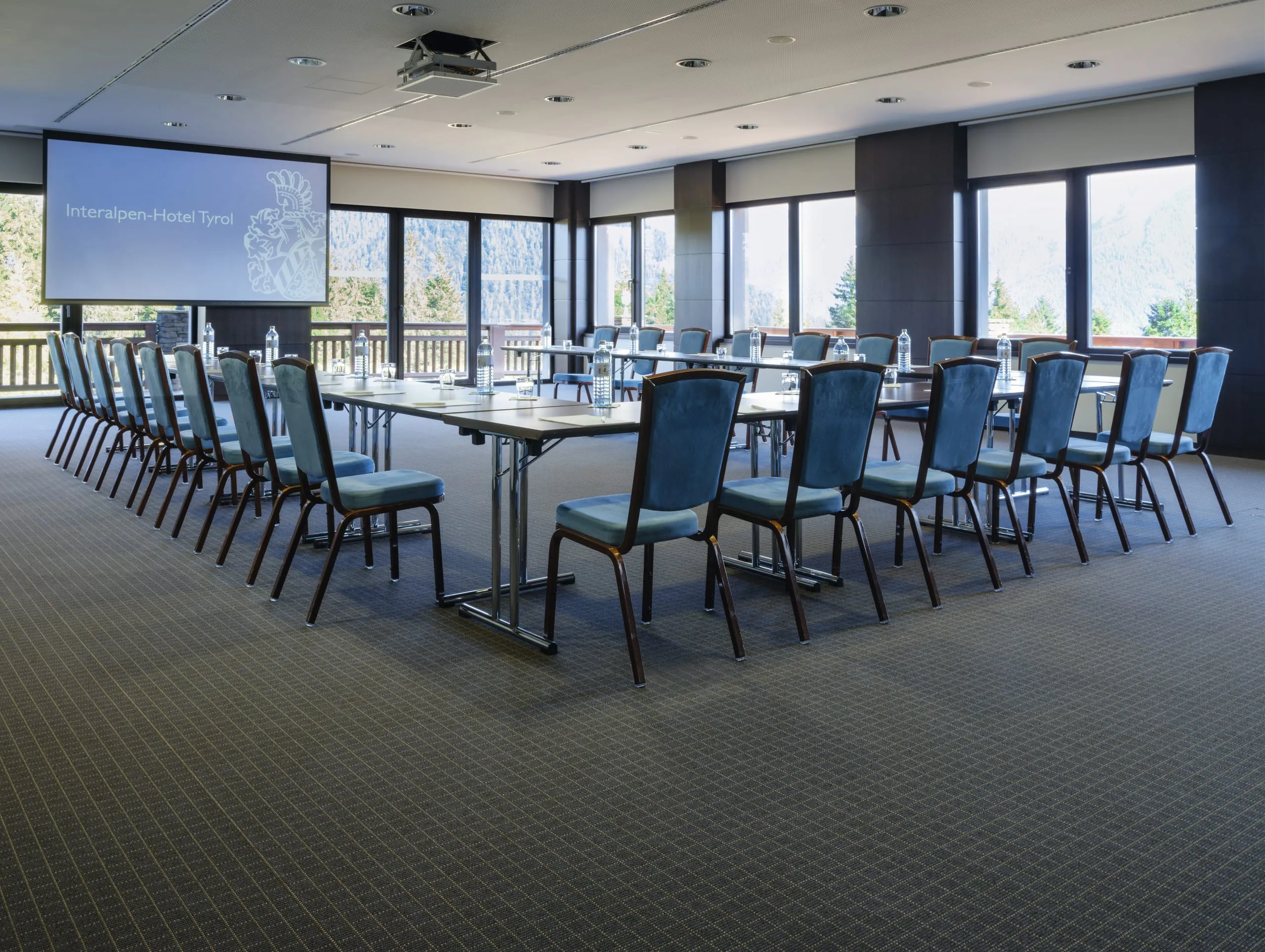 In U-Form mit blauen St&uuml;hlen bestuhlter Konferenzraum
