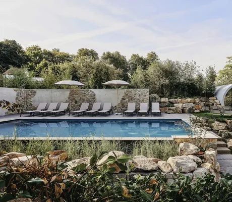 Outdoorpool mit Liegen und Sonnenschirmen im Naturgarten mit Bruchsteinen im Landhotel Voshövel