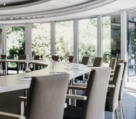 Sitzungssaal mit U-Bestuhlung beiger Stühle vor geschwungener Fensterfront im Landhotel Voshövel