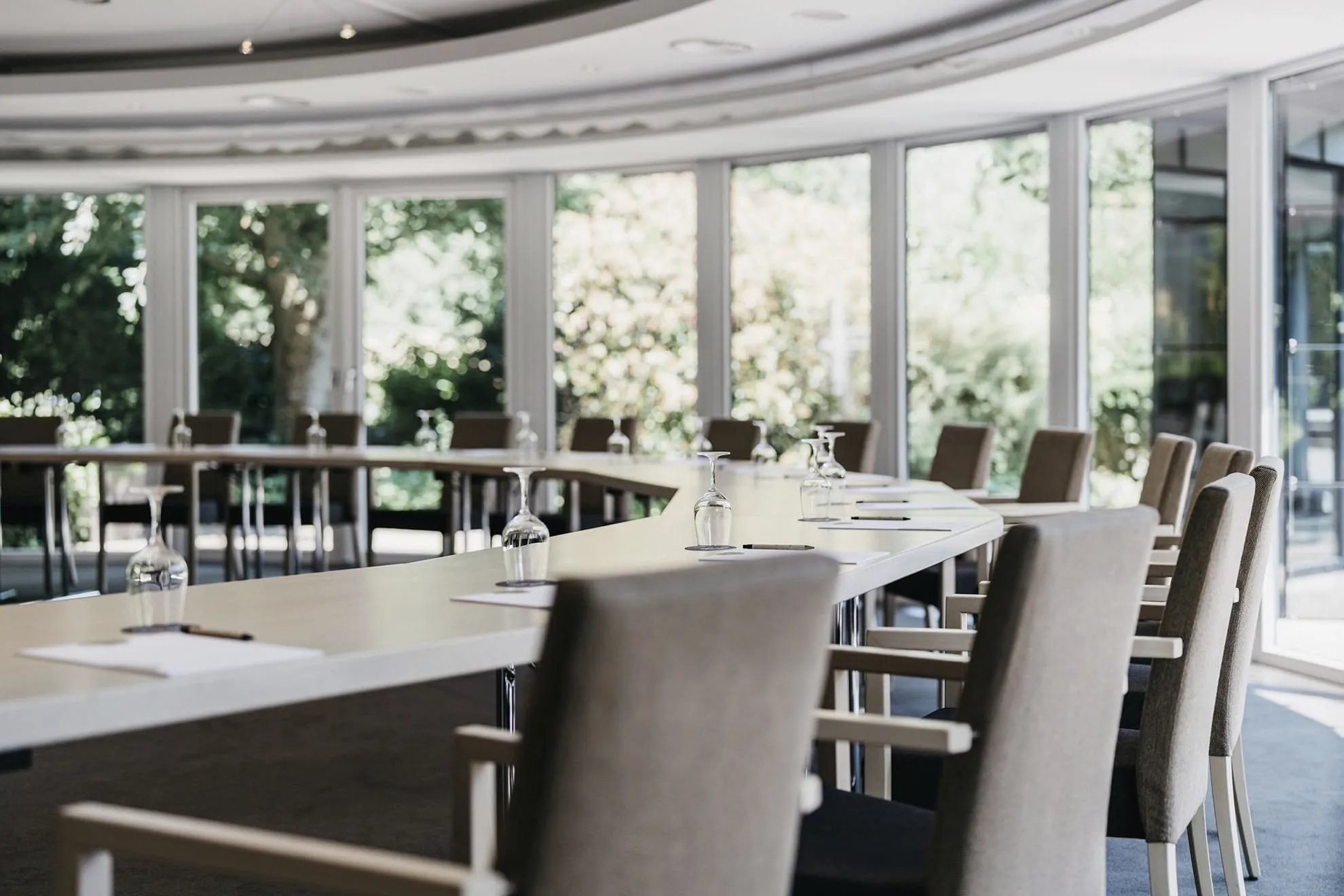 Sitzungssaal mit U-Bestuhlung beiger St&uuml;hle vor geschwungener Fensterfront im Landhotel Vosh&ouml;vel