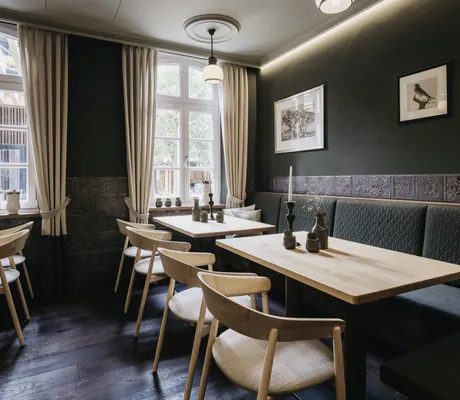 Restaurant mit Holzbestuhlung, grüner Sitzbank und grüner Wandfarbe mit Fenstern in Grüne im Landhotel Voshövel