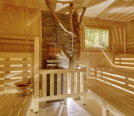 Sauna mit Kessel über dem Saunaofen und Baumstamm