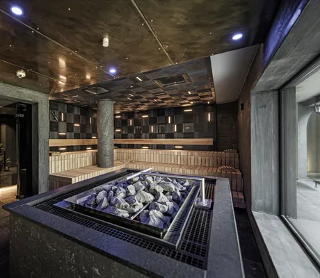 Sauna mit schwarzen Säulen und schwarz verkleideten Wänden mit Saunaofen im Vordergrund