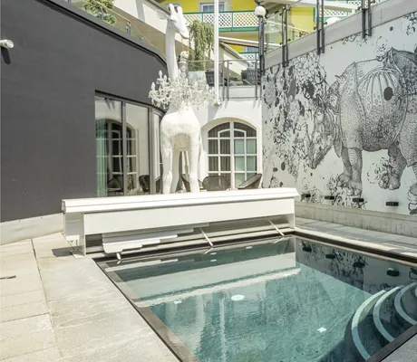 Giraffenskulptur neben Tauchbecken und gezeichnetes Nashorn an der Wand