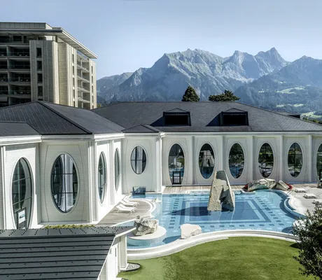 Tamina Therme Außenansicht mit Outdoorpool und ovalen Fensterfronten vor den Schweizer Bergen