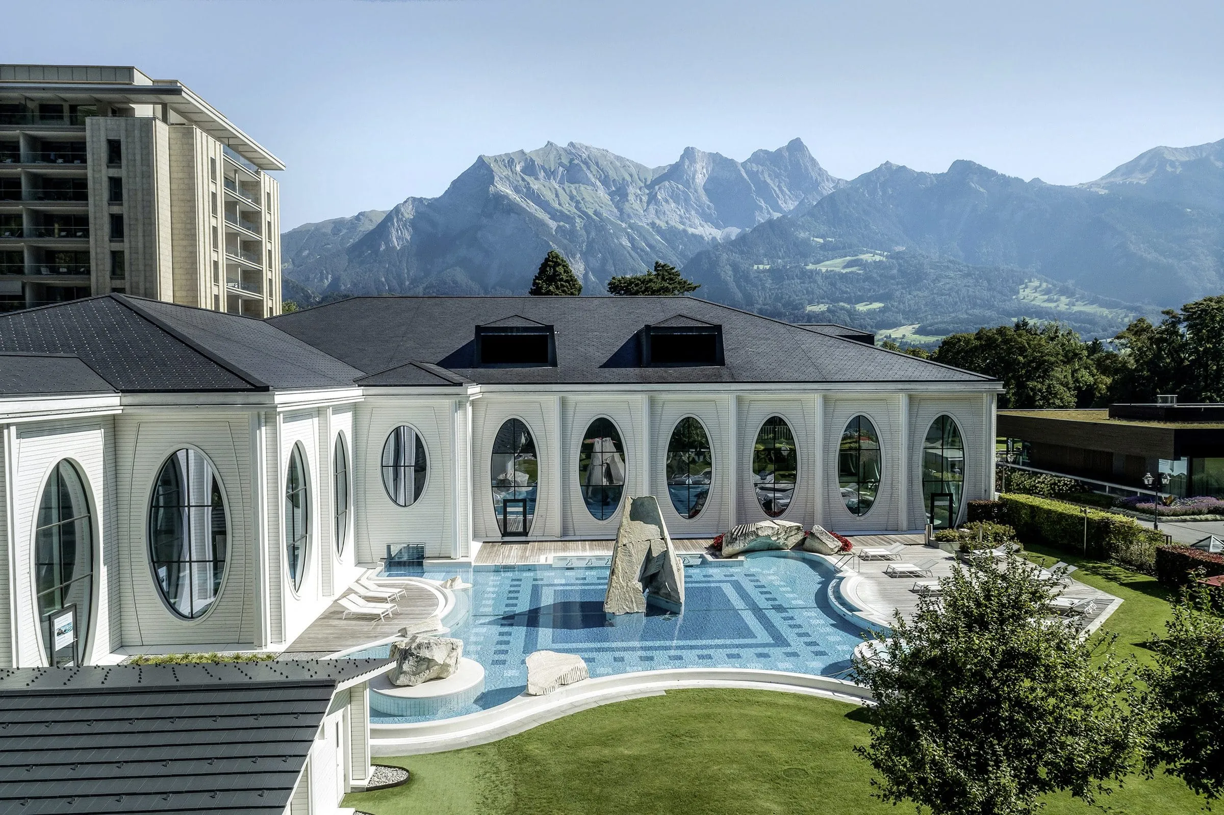 Tamina Therme Au&szlig;enansicht mit Outdoorpool und ovalen Fensterfronten vor den Schweizer Bergen