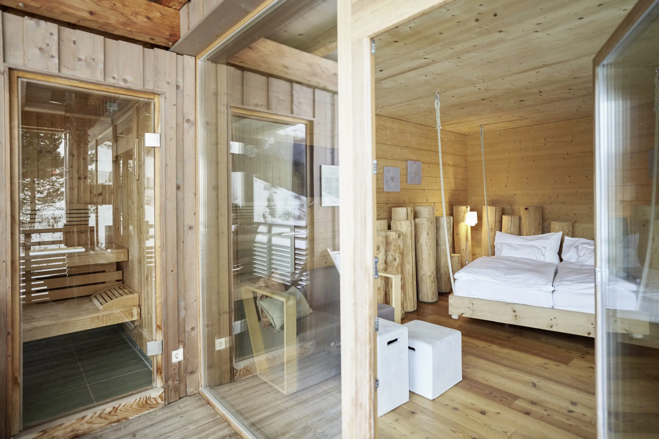 Bett h&auml;ngt an Seilen im Doppelzimmer des Holzhotel Forsthofalm mit eigener Sauna