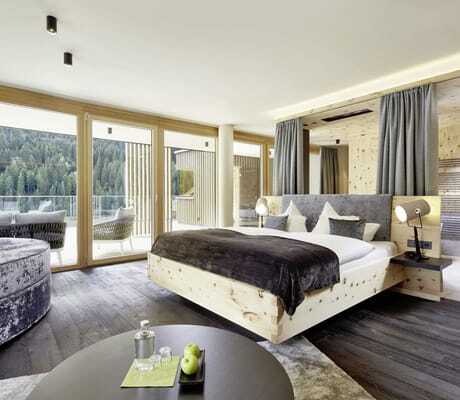 Suite mit Doppelbett und runden grauem Samtsofa im Lürzerhof Alpin Life Resort