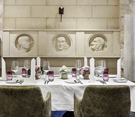 eingedeckter Tisch im Restaurant mit Stein-Porträts berühmter Römer an der Wand im Marc Aurel