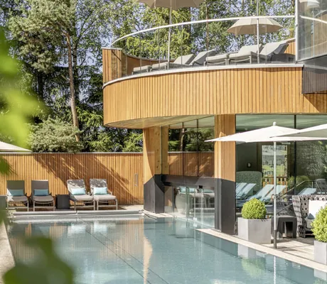 Außenpool mit rundem Holz-Überbau mit Sonnenliegen im Naturhotel Waldklause