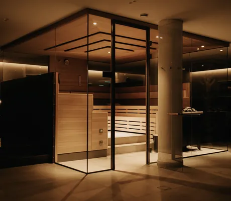 Saunakubus in rötlichem Licht mit Säule davor