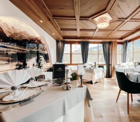 abendlich eingedeckte Tische im Restaurant des Parkhotel Burgmühle mit Kassettendecke