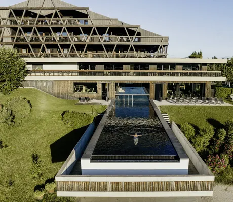Drohnensicht auf Outdoor-Infinitypool des Hotel Pfösl mit Blick auf die Fassade