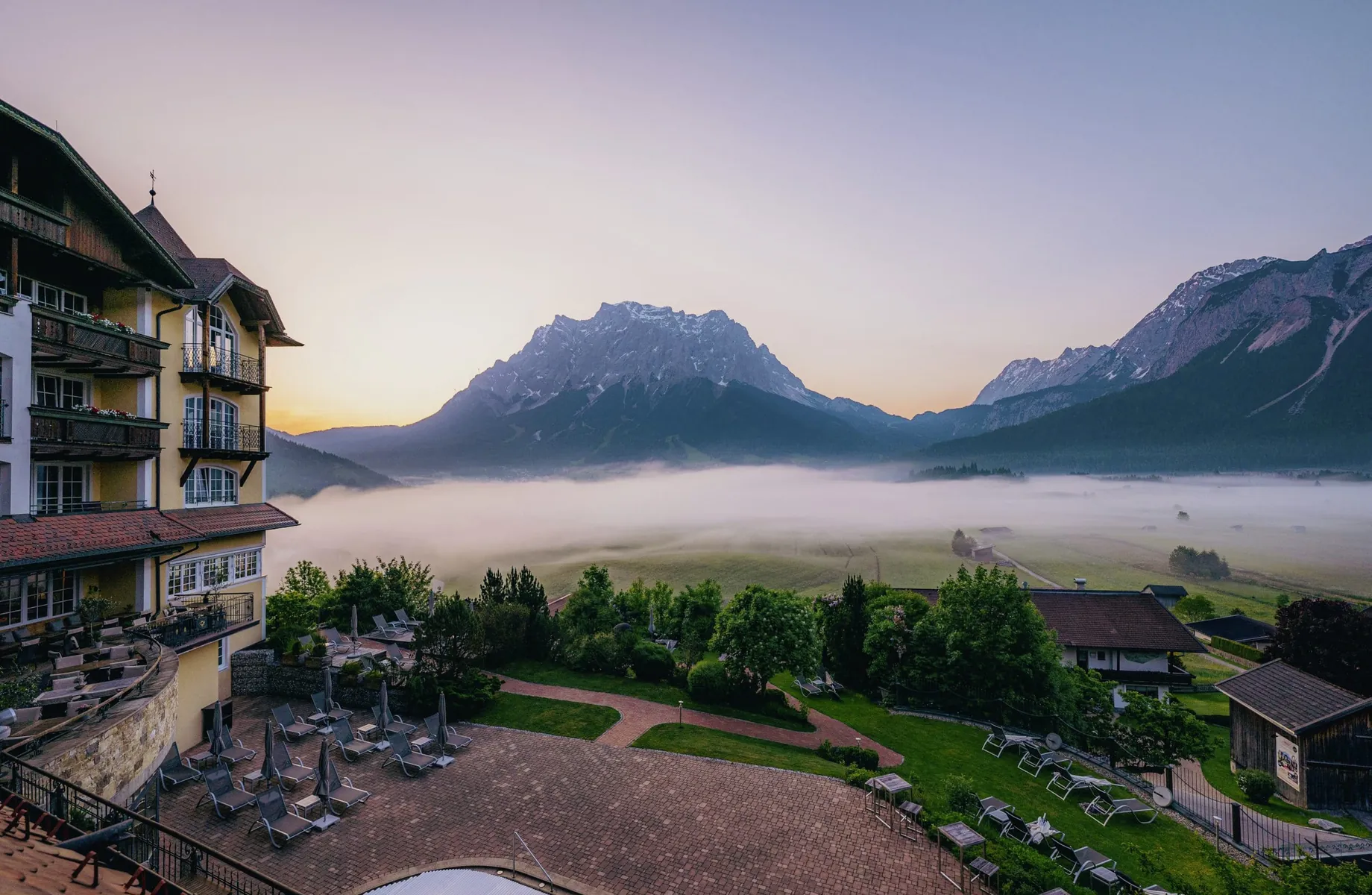 Außenansicht Hotel Post Lermoos mit Nebelschwaden vor den Bergen