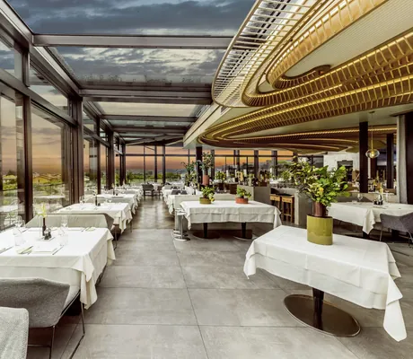 Panoramarestaurant des Quellenhof Luxury Resort Lazise mit goldener Riesenleuchte im Abendrot