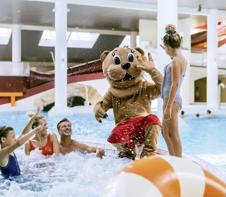 Familie mit zwei Mädchen und dem Hotel-Maskottchen planscht im Schwimmbad des Reiters Allegria