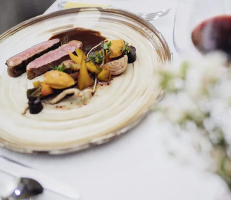 Fleischgericht auf Steingutteller mit Rotweinglas im Reiters Supreme 5* Hotel