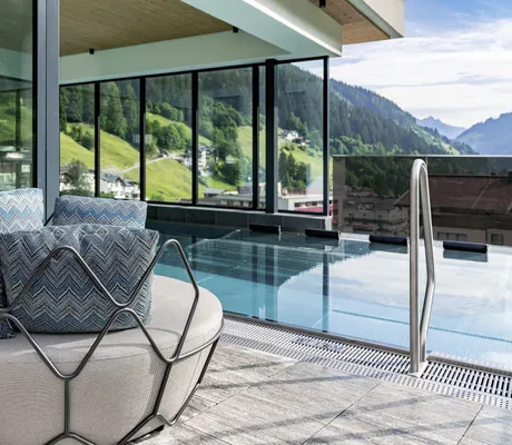 runder Metallkorbsessel mit türkisen Kissen vor Outdoorpool auf dem Rooftop