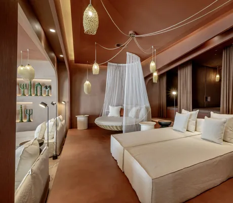 terrakottafarbene Liegekojen mit beigen Leinen-Ruhebetten und Korblampen